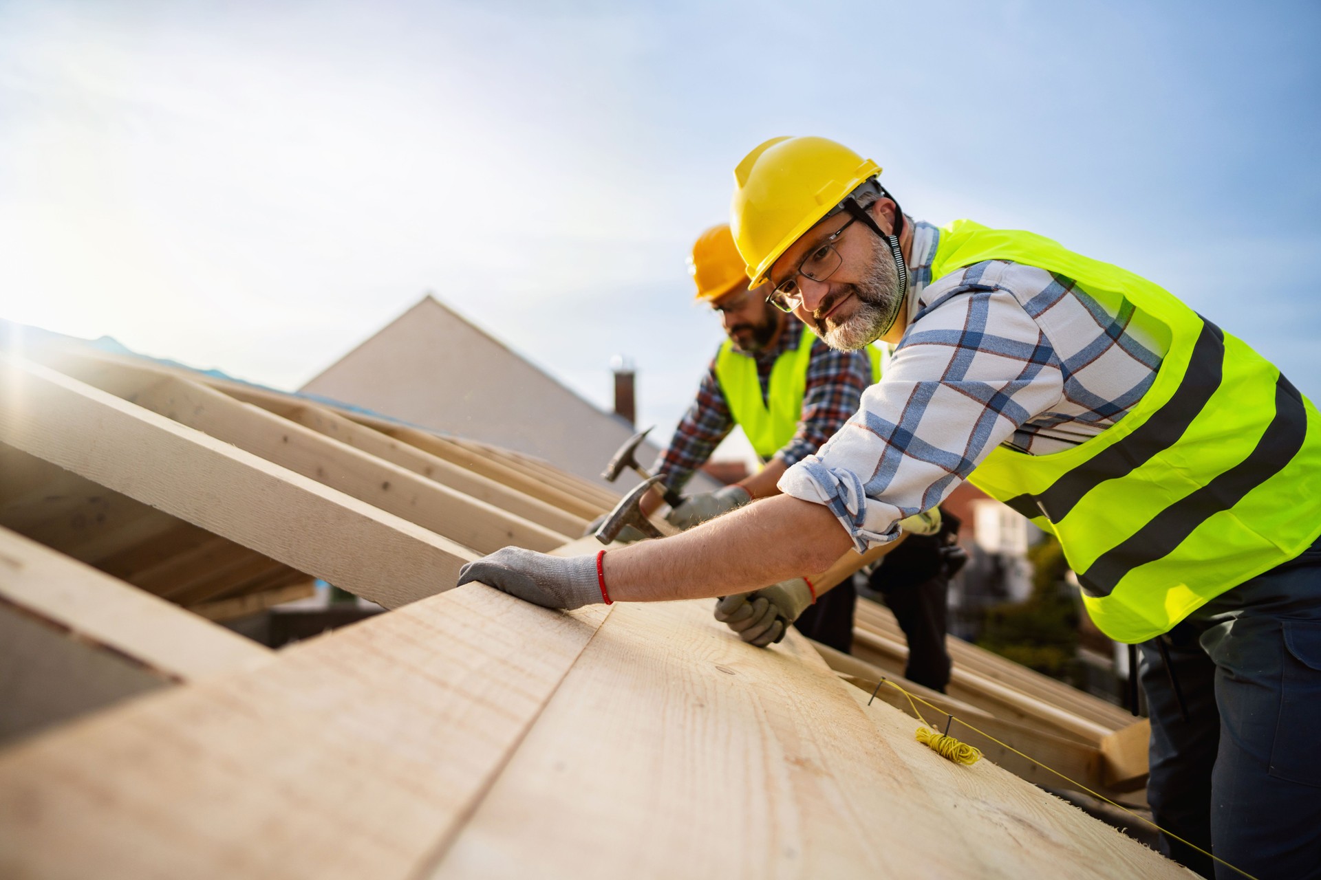 Caucasian roofers, using nails and hammer while making a roof beam